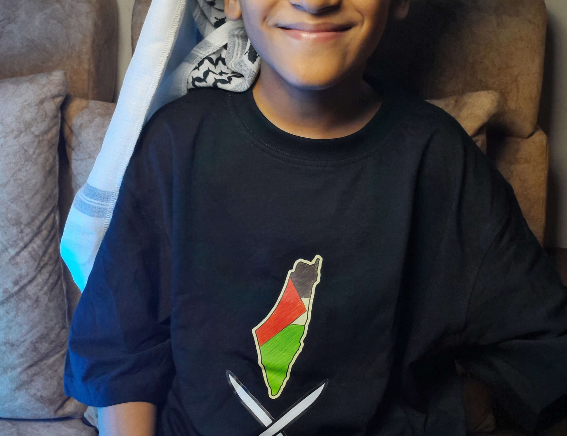 Child wearing a black shirt with a colorful design, sitting on a couch.